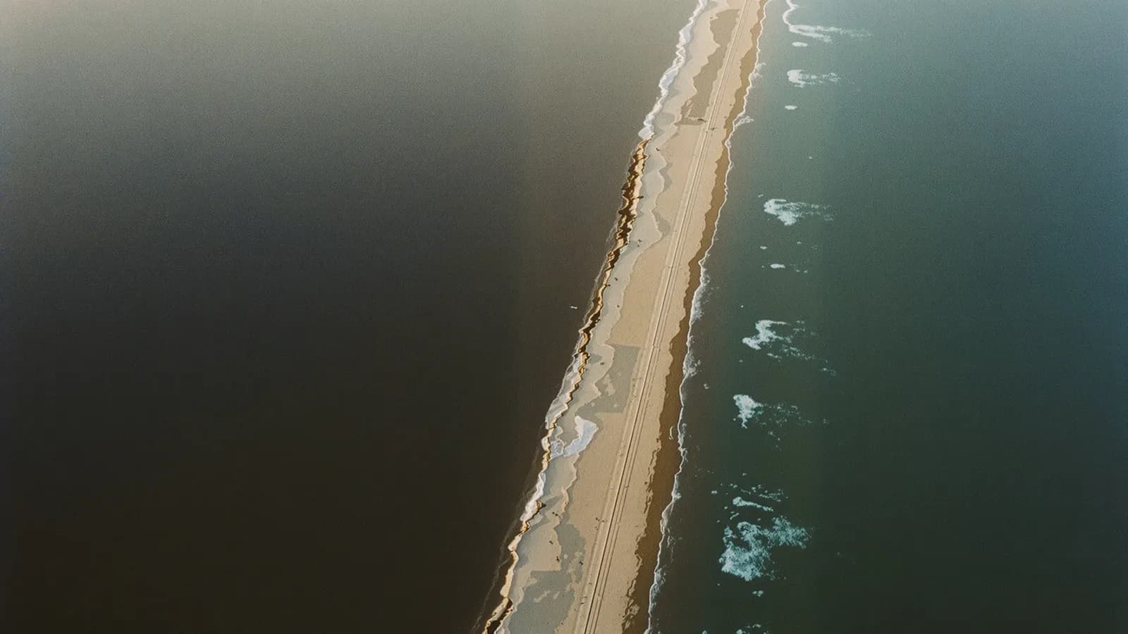 Aerial view of a coastline meeting open sea at golden hour