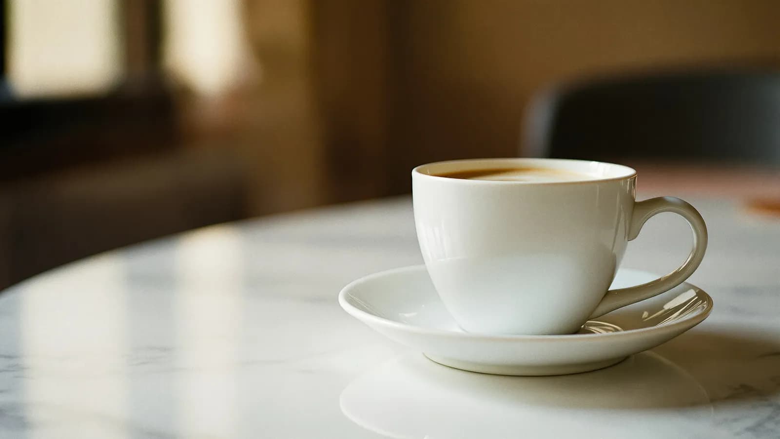 White espresso cup on a marble café table in soft morning light