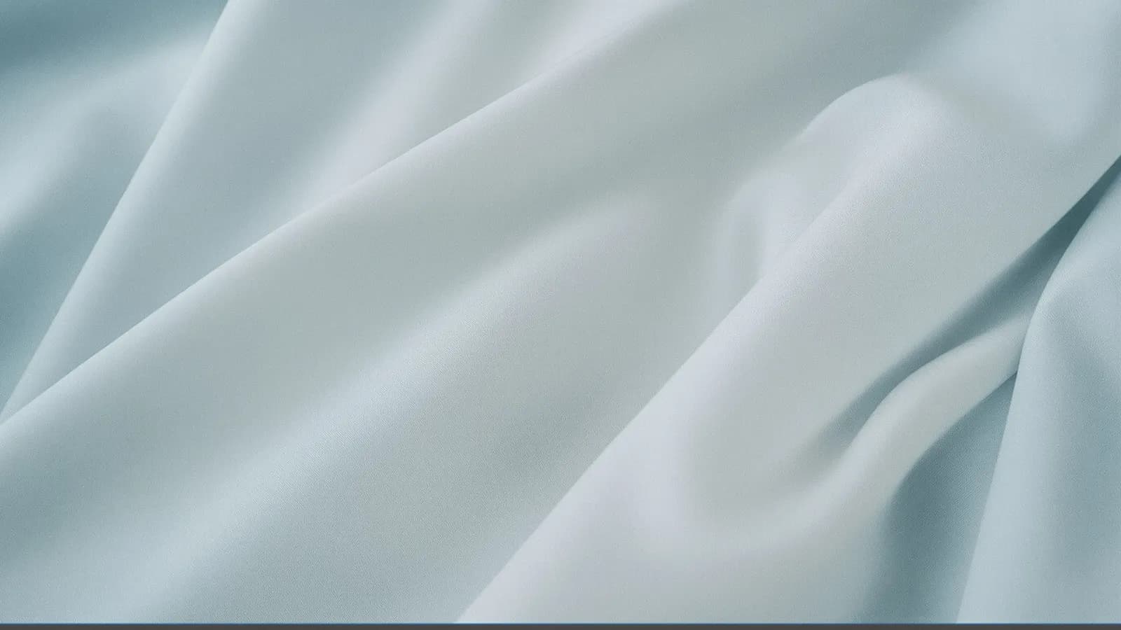 Close-up of pale blue-grey fabric with soft folds under even studio light