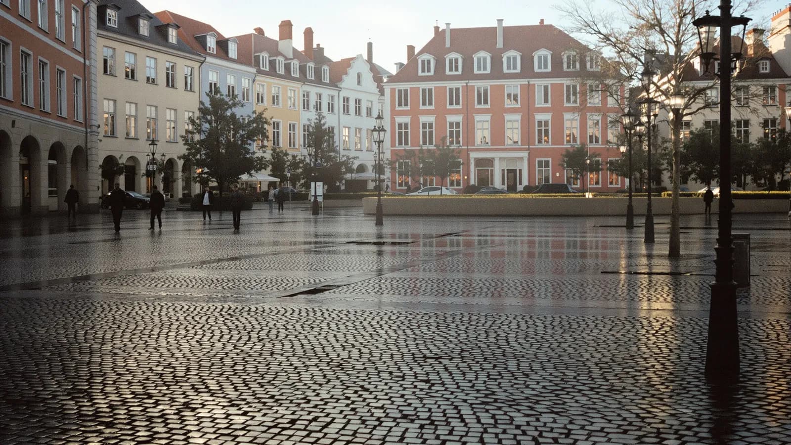 Empty European square at dawn with long shadows across wet cobblestones