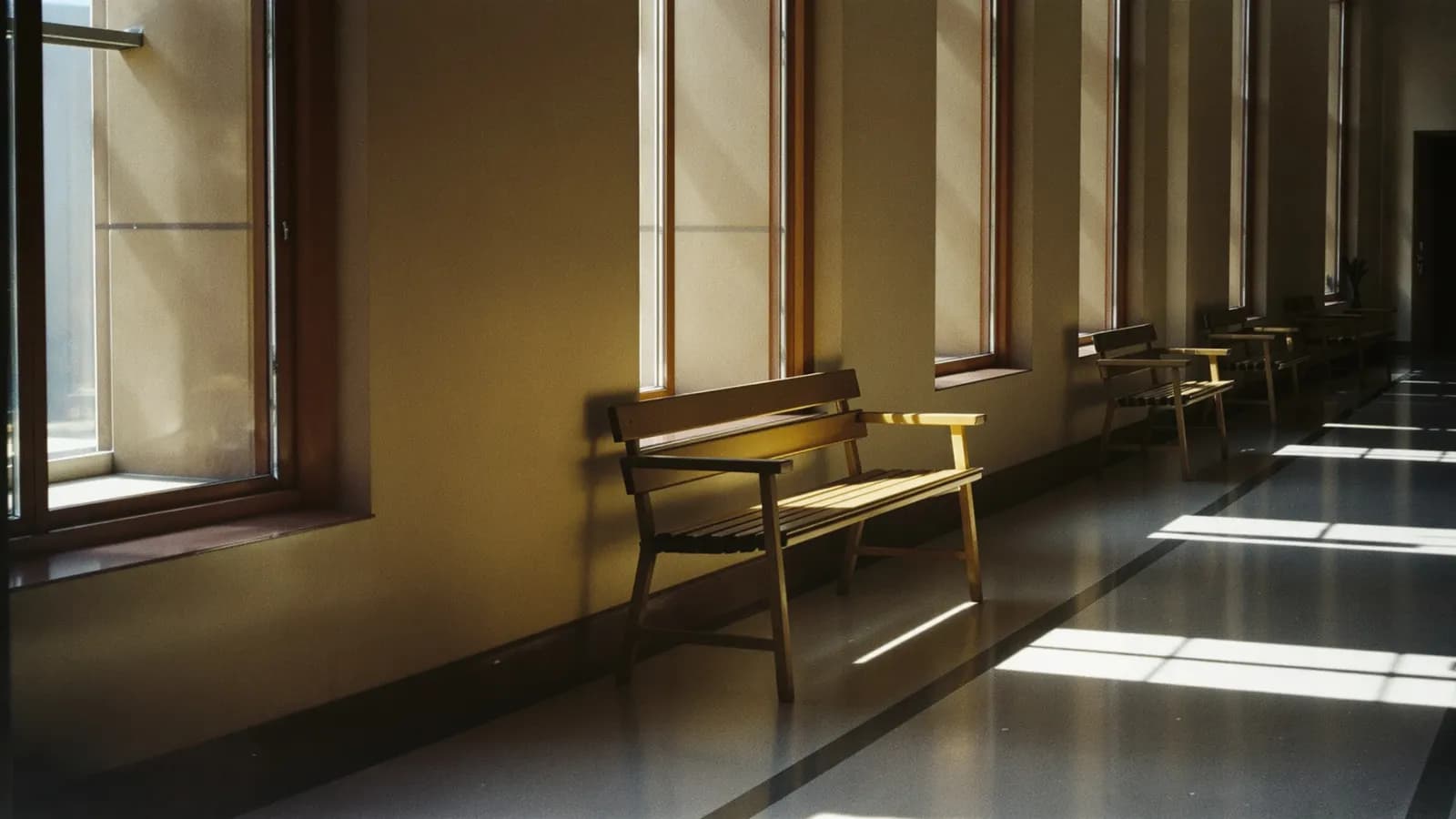 Empty waiting-hall bench beside a tall window with morning light on the floor