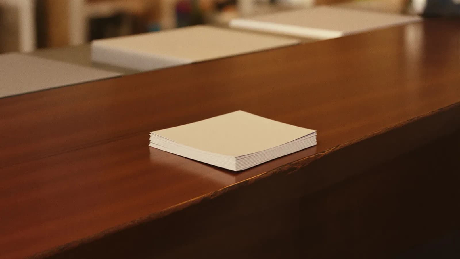 Bank counter detail with a stack of paper slips in warm indoor light